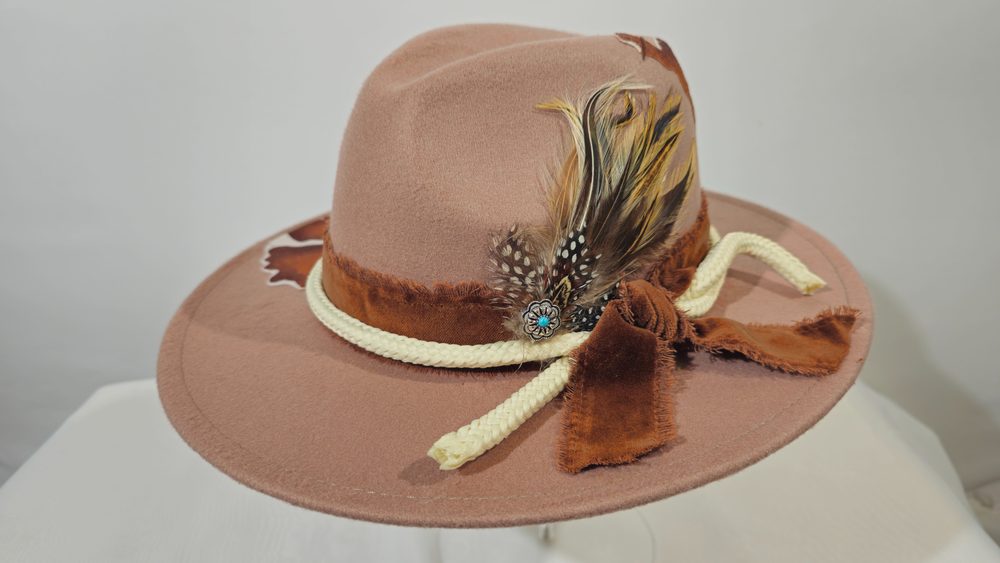 Prairie Oracle — dusty rose western hat with feathers and an asymmetric cow-print panel