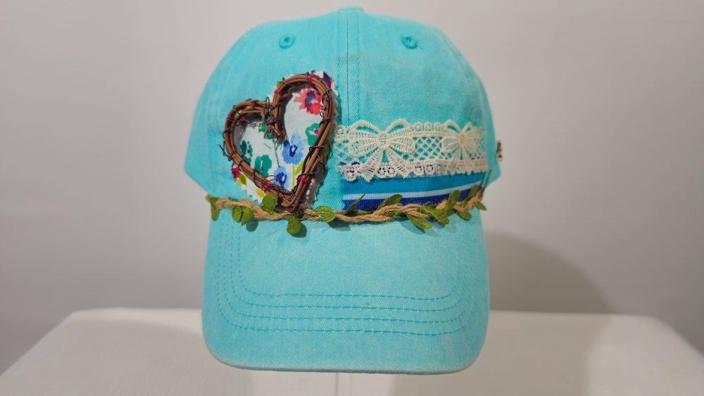 Wildheart — aqua baseball cap with a twig-framed heart, lace, and vine